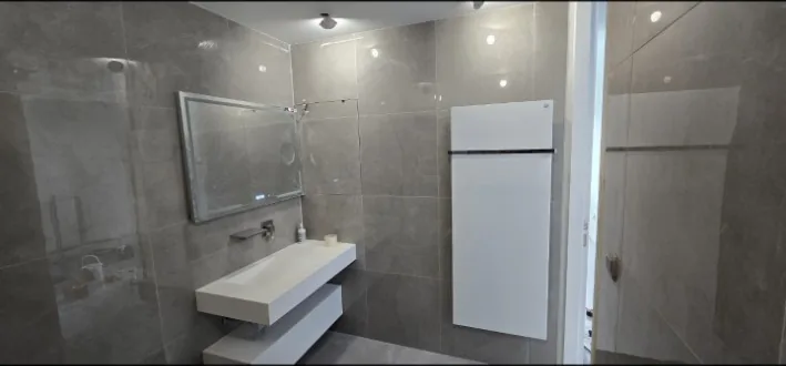 Salle de bain rénovée avec miroir éclairé et sèche-serviettes